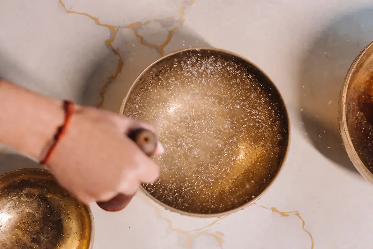 A hand guiding a mallet around a singing bowl during Individual Sound Healing